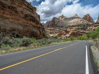 empty road surrounded by cliffs and vegetation in desert area near mountains and trees covered with greenery