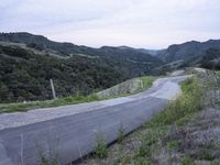 an empty country road winds through hilly countrysides in california, on a cloudy day