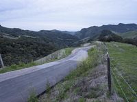 an empty country road winds through hilly countrysides in california, on a cloudy day