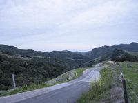 an empty country road winds through hilly countrysides in california, on a cloudy day