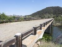 a view from a bridge overlooking trees and a mountain range of hills behind a bridge