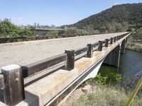 a view from a bridge overlooking trees and a mountain range of hills behind a bridge