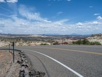 a empty highway with lots of gravel and rocks next to the road with mountains on either side