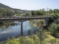 a view from a bridge overlooking trees and a mountain range of hills behind a bridge