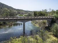 a view from a bridge overlooking trees and a mountain range of hills behind a bridge