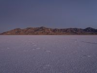 a large expanse of white sand in front of a desert with mountains in the background