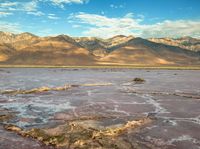 a dirt patch is next to the mountains in a dry plain that is under water