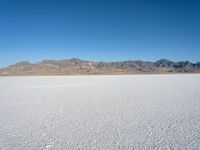 a view of the desert landscape with mountains in the background and snow on the ground