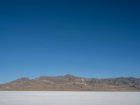 a view of the desert landscape with mountains in the background and snow on the ground