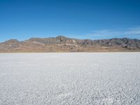 a view of the desert landscape with mountains in the background and snow on the ground