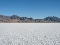 a view of the desert landscape with mountains in the background and snow on the ground