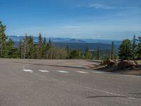 the mountains are visible in the distance from this wide, empty road, overlooking a wide landscape and forest