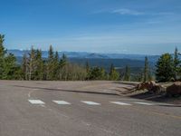 the mountains are visible in the distance from this wide, empty road, overlooking a wide landscape and forest