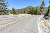 a man riding a scooter down a winding mountain road next to trees and a rock