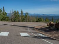 the mountains are visible in the distance from this wide, empty road, overlooking a wide landscape and forest