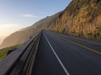 the road winds down the side of the mountain to the sea side, surrounded by mountains