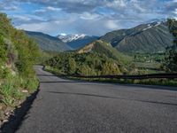 the road winds up on the mountainside on a sunny day with beautiful clouds and trees