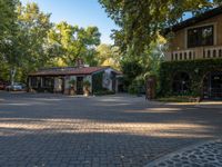 a courtyard has many trees surrounding it and cars parked on the side of it on the side