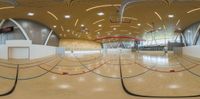 a sports hall with a red basketball court and blue walls and flooring and lots of lights