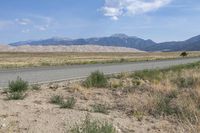 a dirt road and a large mountain range near a desert area, with the side road to the right