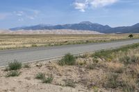 a dirt road and a large mountain range near a desert area, with the side road to the right