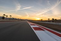 a photo of a dirt race track with sun setting in the distance of the track