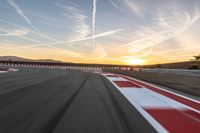 a photo of a dirt race track with sun setting in the distance of the track