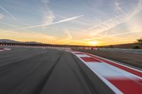 a photo of a dirt race track with sun setting in the distance of the track