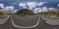 a view from a 360 - angle to a scenic empty road with rocks and shrubs