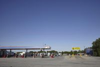 a gas station is empty with truck parked in the lot near it and a sign that reads,