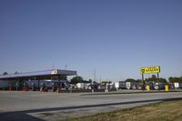 a gas station is empty with truck parked in the lot near it and a sign that reads,