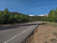 an empty road with lots of trees in the background in the wild region of colorado