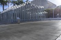 a street scene in a city with light poles and palm trees on the sidewalk and a bench