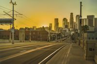 an empty highway with power lines leading to city buildings in the back ground and road tracks