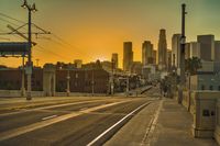 an empty highway with power lines leading to city buildings in the back ground and road tracks