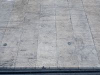 a concrete skateboarder performs the trick in front of an empty ramp during the day