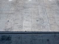 a concrete skateboarder performs the trick in front of an empty ramp during the day