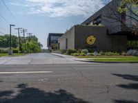 a building with a logo painted on the side near a street that has a sidewalk next to it