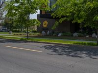 a building with a logo painted on the side near a street that has a sidewalk next to it