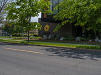 a building with a logo painted on the side near a street that has a sidewalk next to it