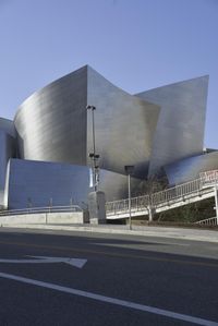 an empty street near a cityscape and futuristic buildings with advertisements on the side of the buildings
