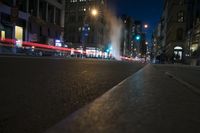 a street with cars parked at an intersection, on a busy night time in a city