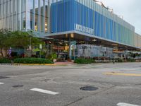 an empty intersection in front of a glass building with multi - colored architecture on it