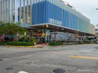 an empty intersection in front of a glass building with multi - colored architecture on it