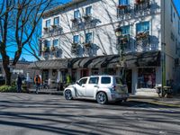 a street corner with shops, benches, and chairs on each side of the street