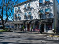 a street corner with shops, benches, and chairs on each side of the street