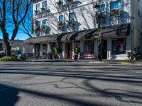 a street corner with shops, benches, and chairs on each side of the street