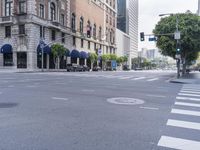 an empty street with several vehicles at the crosswalk and a light post and a building