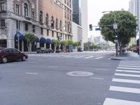 an empty street with several vehicles at the crosswalk and a light post and a building