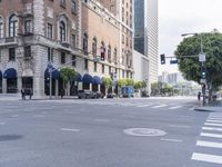 an empty street with several vehicles at the crosswalk and a light post and a building